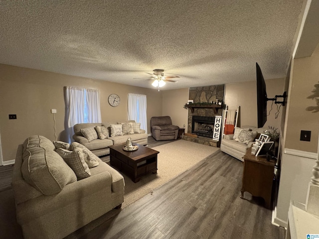 living room featuring a ceiling fan, a textured ceiling, wood finished floors, and a fireplace