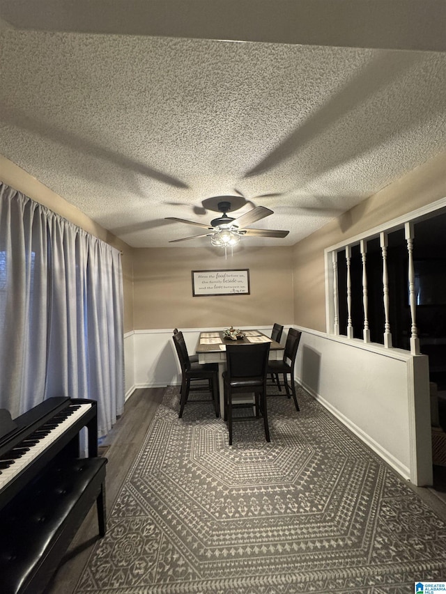 dining room featuring wood finished floors, a ceiling fan, baseboards, and a textured ceiling