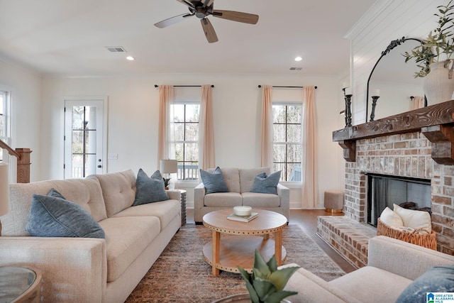 living room with plenty of natural light, a fireplace, visible vents, and ornamental molding