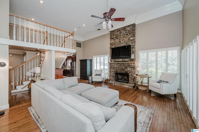 living area featuring stairway, crown molding, a towering ceiling, and wood-type flooring