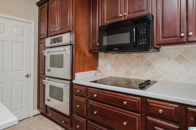 kitchen featuring black appliances, light tile patterned floors, light countertops, and tasteful backsplash