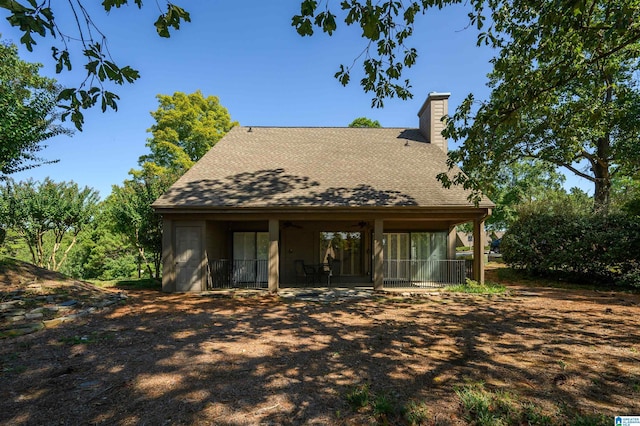 back of house featuring a shingled roof, a patio, and a chimney