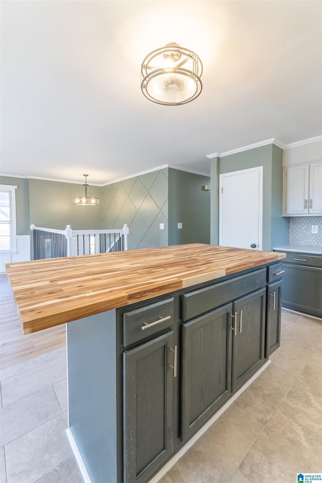 kitchen with decorative backsplash, crown molding, an inviting chandelier, and butcher block counters