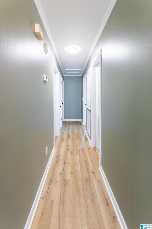 hall with light wood-style flooring, baseboards, and ornamental molding