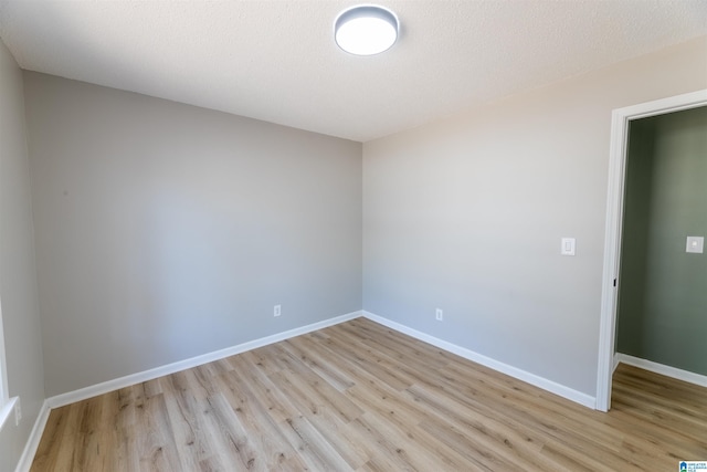 unfurnished room featuring light wood finished floors, a textured ceiling, and baseboards