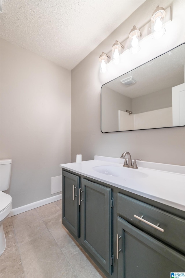 bathroom with vanity, baseboards, tile patterned flooring, a textured ceiling, and toilet