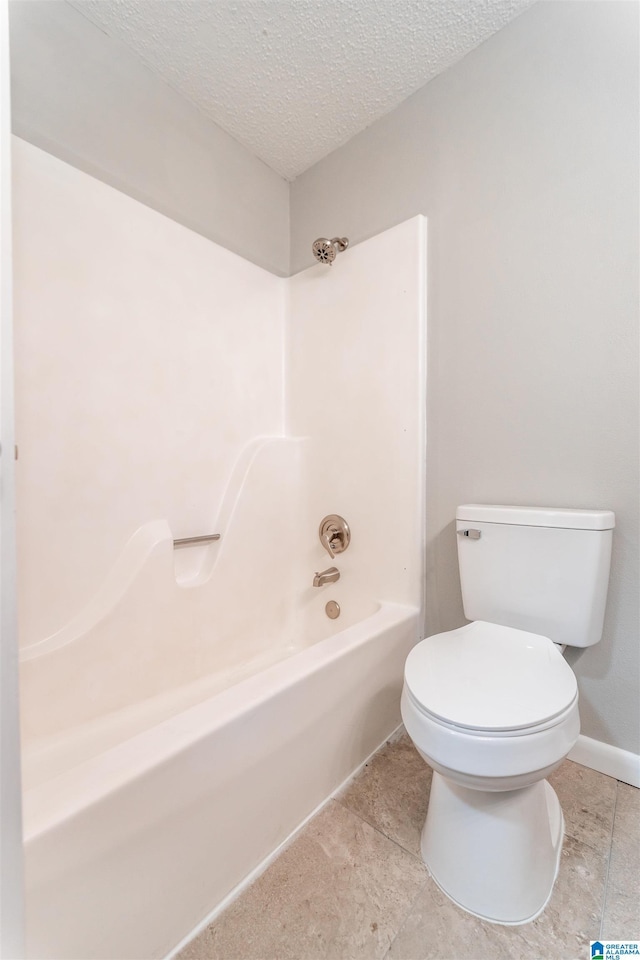 full bathroom with tile patterned flooring, baseboards, toilet, shower / tub combination, and a textured ceiling