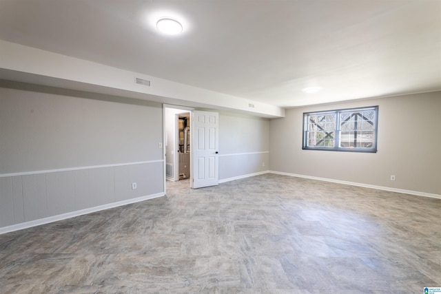 below grade area with a wainscoted wall, baseboards, and visible vents