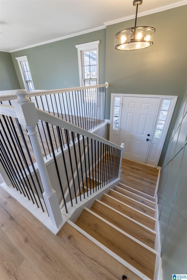 stairway with crown molding and wood finished floors