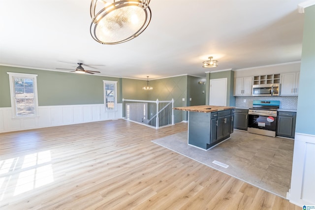 kitchen featuring wooden counters, appliances with stainless steel finishes, light wood-type flooring, and ornamental molding