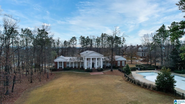 greek revival house with a front yard, a fenced in pool, and fence