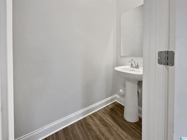 bathroom with a sink, baseboards, and wood finished floors