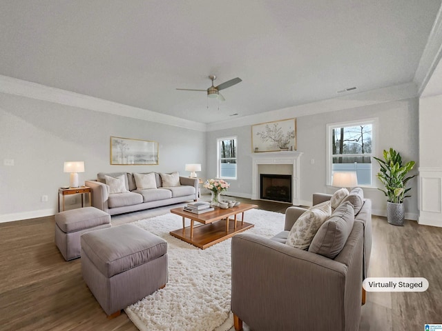 living room with ceiling fan, visible vents, wood finished floors, and crown molding