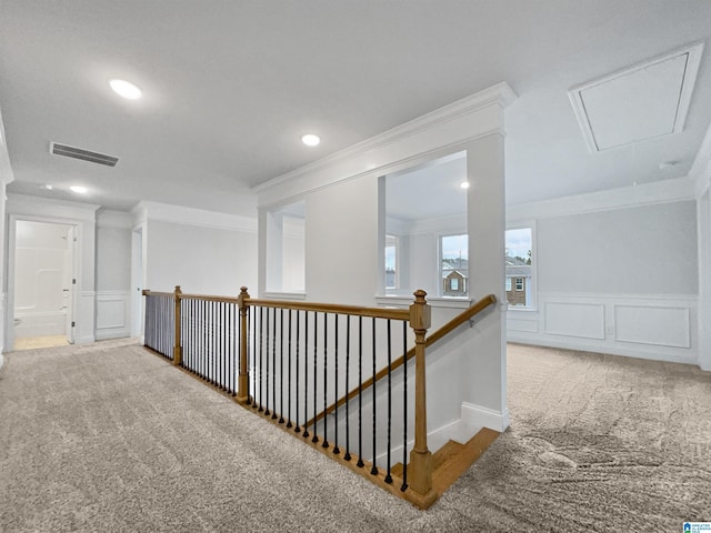 corridor featuring attic access, visible vents, carpet floors, and ornamental molding