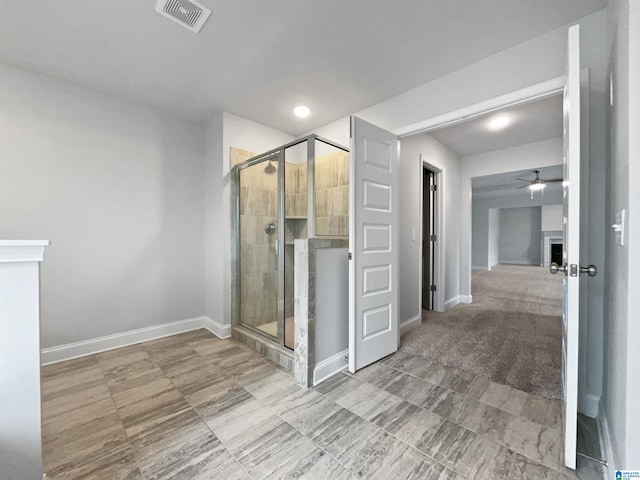 bathroom with visible vents, a shower stall, baseboards, ceiling fan, and a fireplace