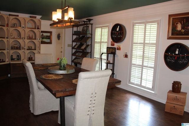 dining space with a notable chandelier, dark wood-style floors, and ornamental molding