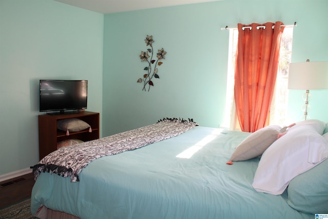 bedroom featuring visible vents, baseboards, and wood finished floors