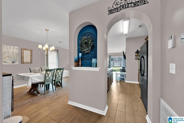 interior space featuring an inviting chandelier, light wood-style flooring, and baseboards