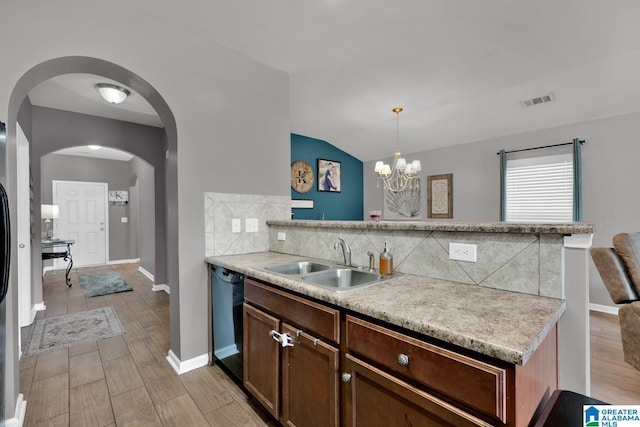 kitchen featuring a peninsula, arched walkways, a sink, black dishwasher, and backsplash