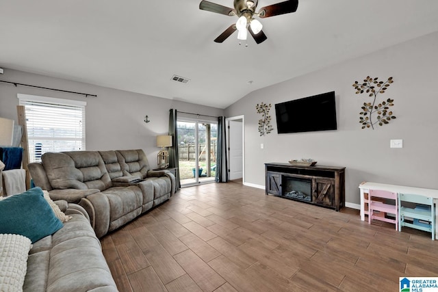 living room featuring visible vents, wood finished floors, baseboards, a fireplace, and lofted ceiling