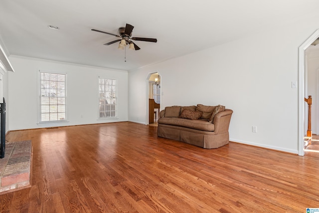 unfurnished room featuring a ceiling fan, arched walkways, crown molding, light wood finished floors, and baseboards