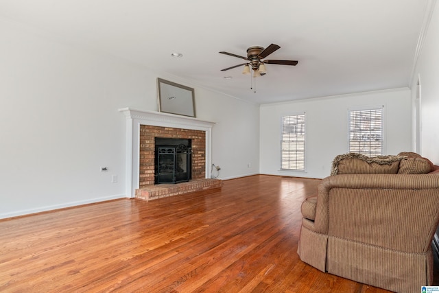 living room with crown molding, baseboards, light wood-type flooring, and a ceiling fan