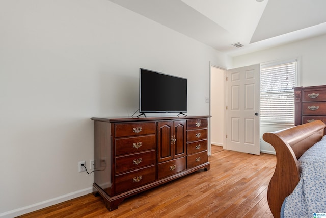 bedroom featuring visible vents, light wood-style flooring, lofted ceiling, and baseboards