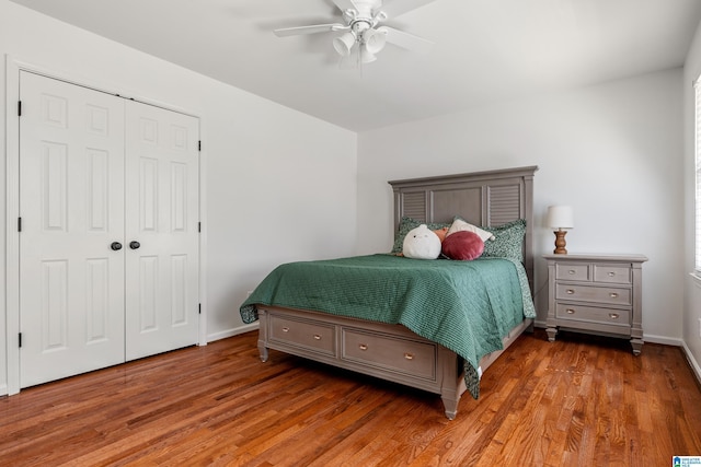 bedroom featuring a closet, baseboards, wood finished floors, and a ceiling fan