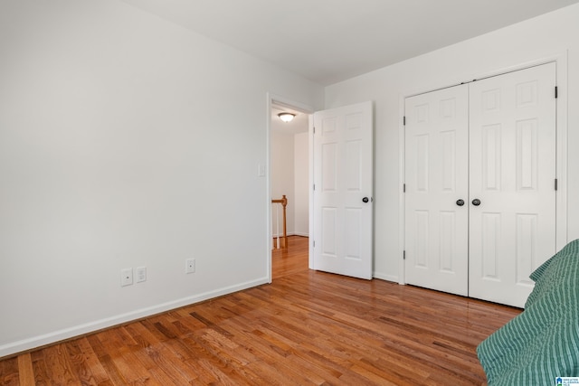 unfurnished bedroom featuring a closet, baseboards, and light wood-style floors