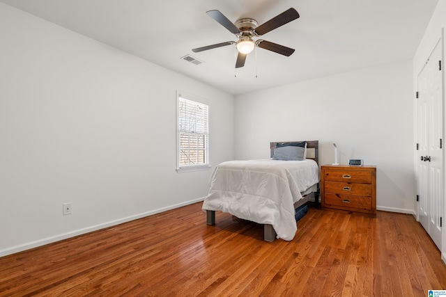 bedroom featuring visible vents, a ceiling fan, baseboards, and wood finished floors