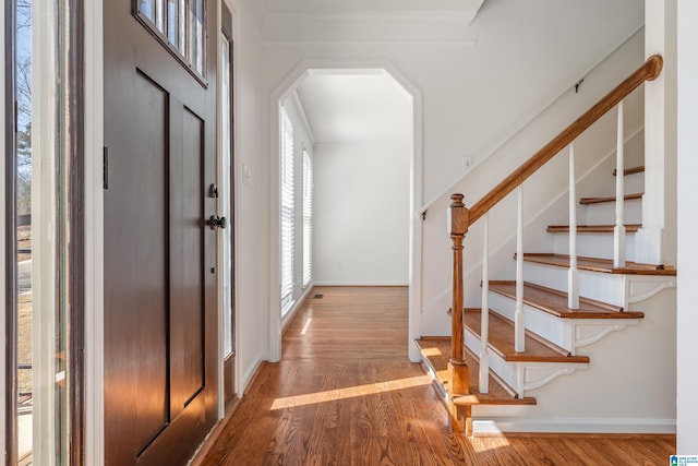 foyer entrance featuring baseboards, wood finished floors, and stairs