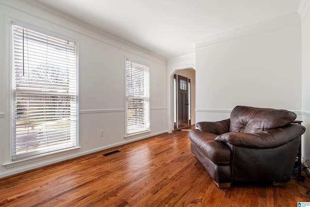 sitting room featuring crown molding, wood finished floors, arched walkways, and visible vents