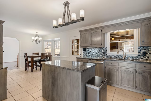 kitchen with stainless steel dishwasher, a notable chandelier, light tile patterned flooring, and a sink