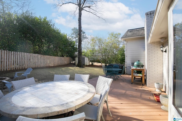 deck featuring fence private yard, an outbuilding, a storage shed, and outdoor dining space