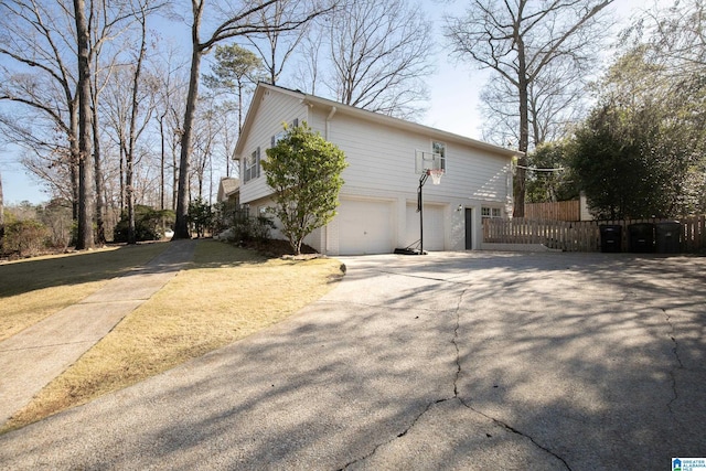 view of side of property featuring an attached garage, concrete driveway, and fence