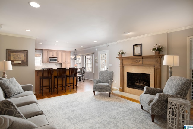 living area with crown molding, light wood-style flooring, a healthy amount of sunlight, and a high end fireplace