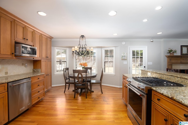 kitchen with plenty of natural light, light wood-style floors, tasteful backsplash, and appliances with stainless steel finishes