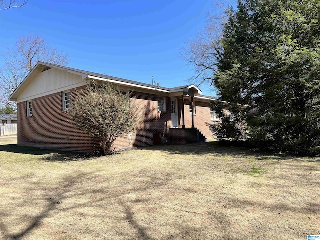 view of home's exterior with brick siding and a yard