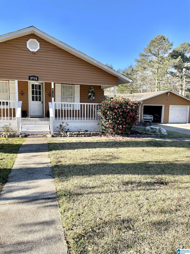 view of front of property with a porch, a front lawn, a detached garage, and an outdoor structure