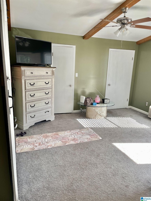 unfurnished living room featuring beamed ceiling, a ceiling fan, baseboards, and carpet floors