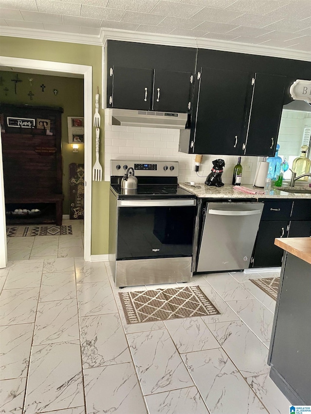 kitchen with marble finish floor, under cabinet range hood, dark cabinetry, appliances with stainless steel finishes, and crown molding