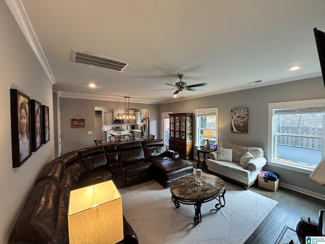 living area featuring a wealth of natural light, visible vents, and ornamental molding