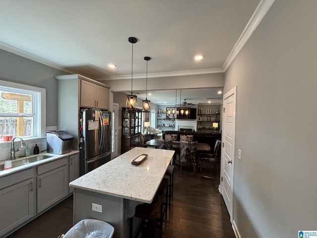 kitchen with a center island, gray cabinets, a kitchen breakfast bar, freestanding refrigerator, and a sink