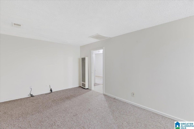 unfurnished room with visible vents, a textured ceiling, and carpet