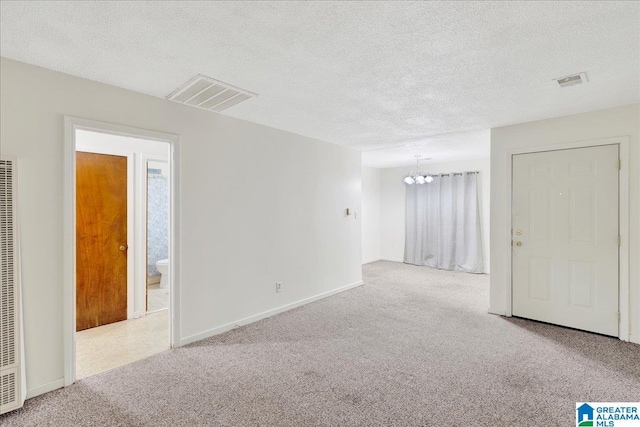 empty room featuring carpet, visible vents, and a textured ceiling