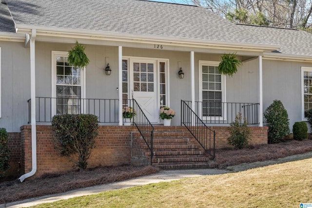 entrance to property with covered porch and roof with shingles