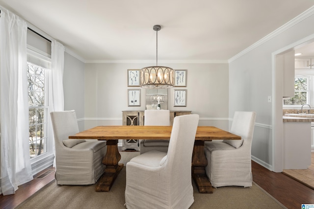 dining space with crown molding, a notable chandelier, wood finished floors, and visible vents