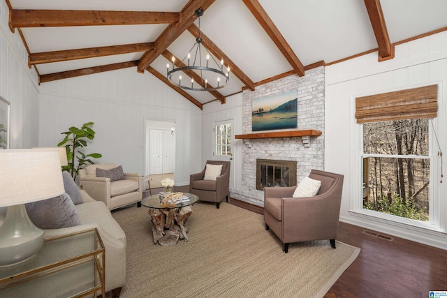 living area featuring visible vents, lofted ceiling with beams, wood finished floors, an inviting chandelier, and a fireplace