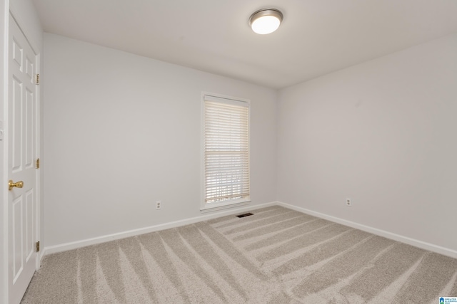 carpeted spare room with visible vents and baseboards