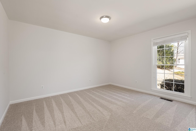 carpeted spare room with visible vents and baseboards